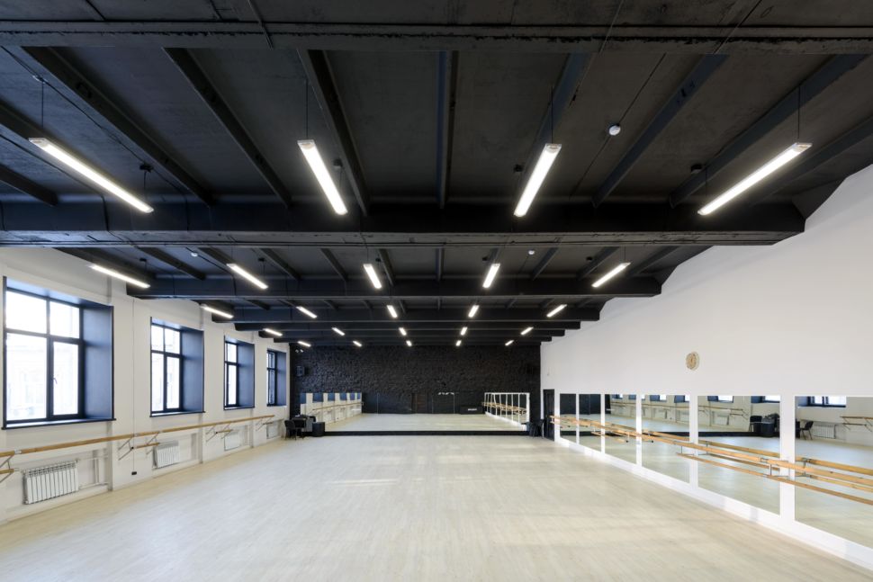 Фотография интерьера танцевального зала 210 кв.м, белый логотип, зеркала, черный окрашенный кирпич, черный потолок, подвесные светильники, двери, радиаторы