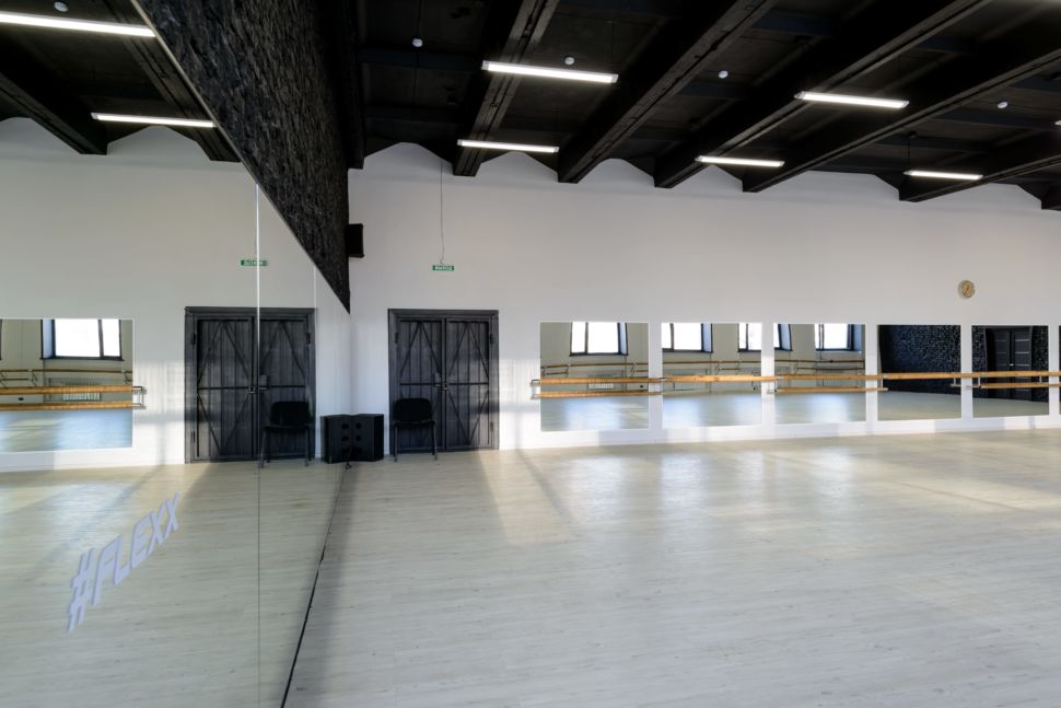 Фотография интерьера танцевального зала 210 кв.м, черный кирпич, белый логотип, зеркала, черный потолок, подвесные светильники, стул, паркет