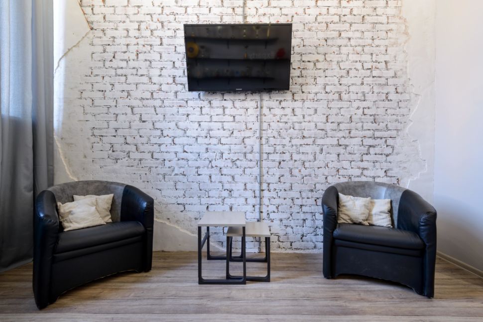 Реализация интерьера комнаты отдыха 13 кв.м в стиле лофт, кирпич окрашенный в белый цвет, кресло, журнальный столик